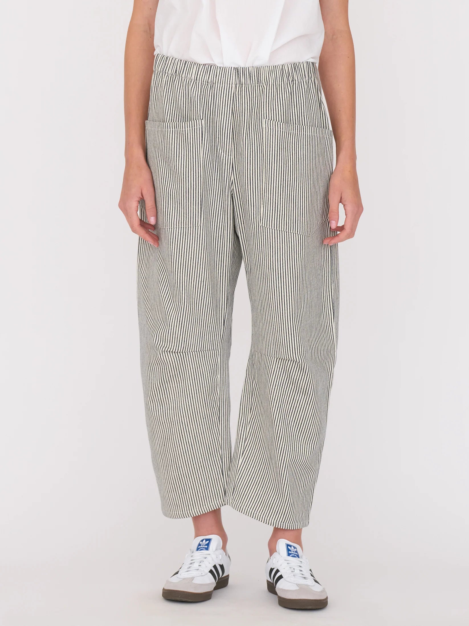 Woman wearing a white blouse and railroad stripe pants by Secular on a white background