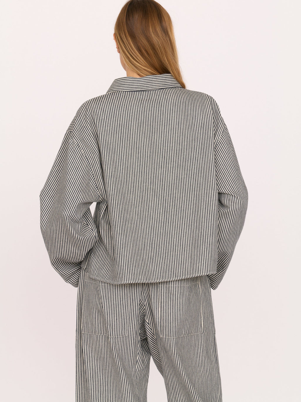 Woman wearing a gray railroad striped walker top by Secular on a white background