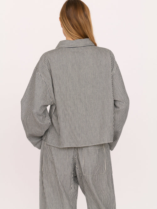 Woman wearing a gray railroad striped walker top by Secular on a white background