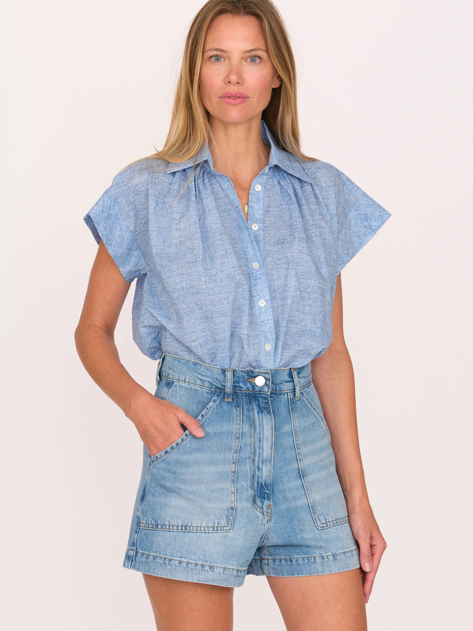 Woman wearing a blue shirt and denim shorts by Secular on a white background