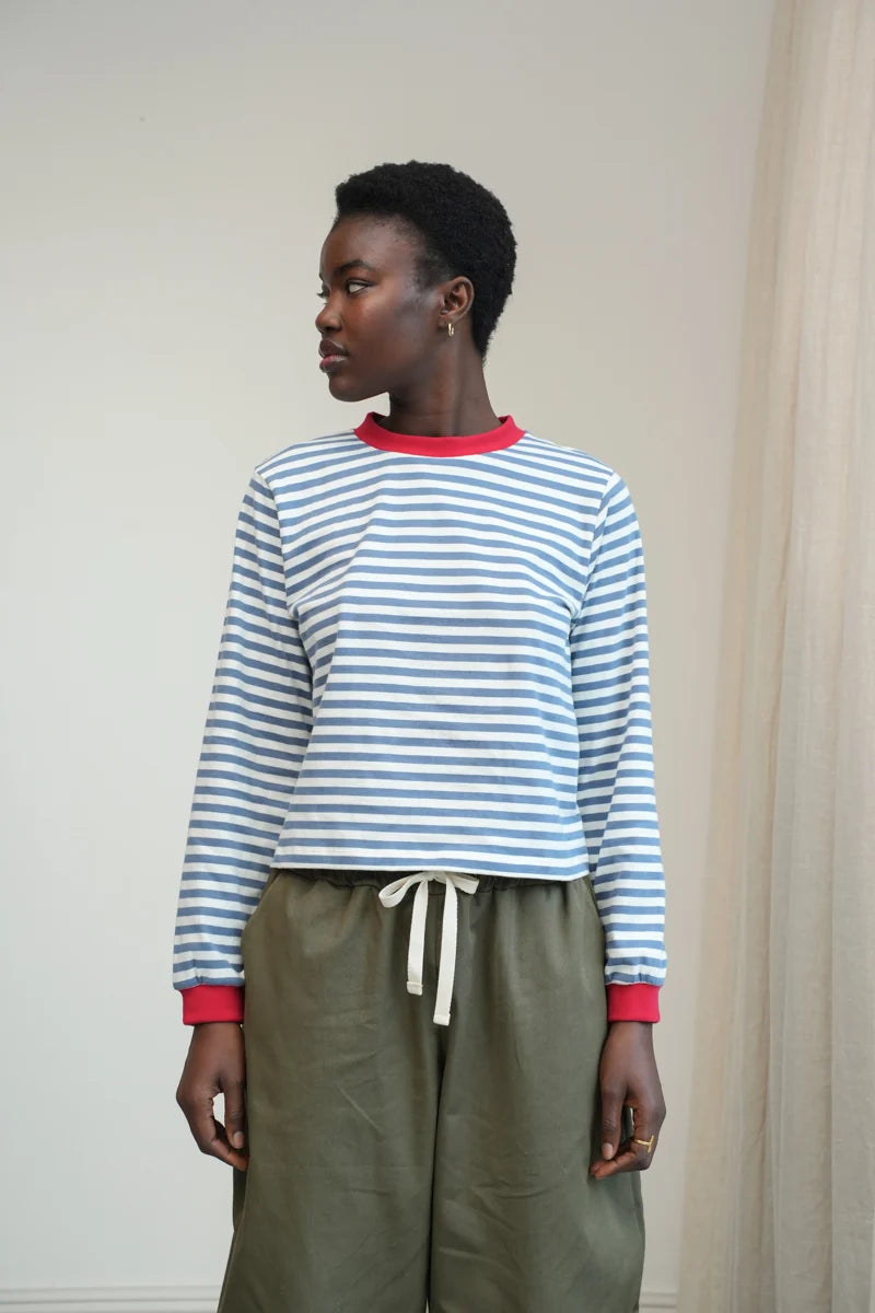 A Model wearing a striped Sierra Sue Long Sleeve T-shirt in Pewter Blue/off white and contrast red collar/ cuffs by Beaumont Organic.