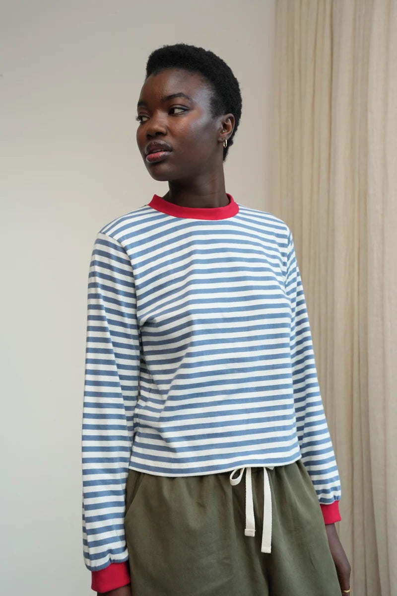 A Model wearing a striped Sierra Sue Long Sleeve T-shirt in Pewter Blue/off white and contrast red collar/ cuffs by Beaumont Organic.