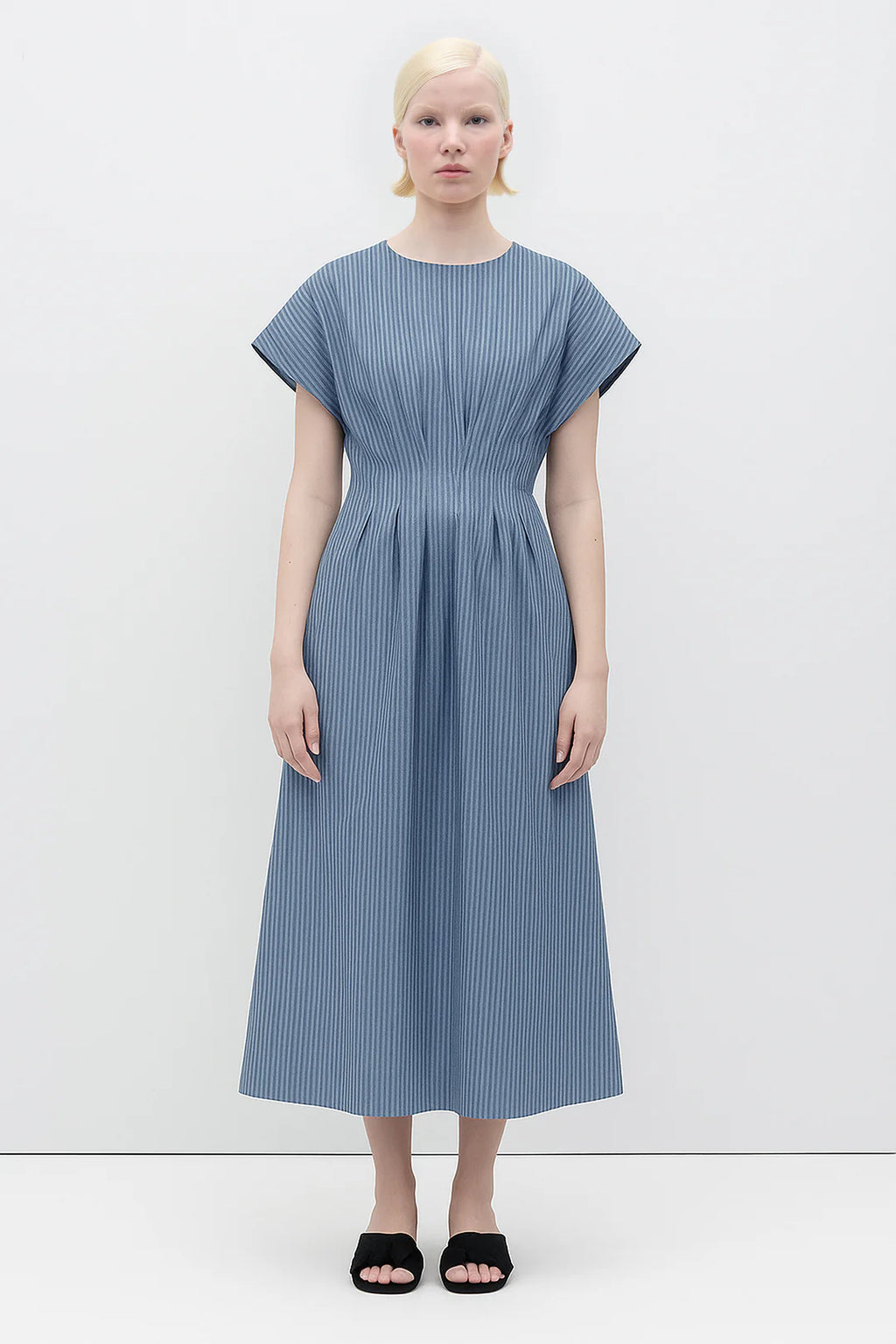Woman wearing a Sybille Dress with blue stripes by Rita Row against a white background