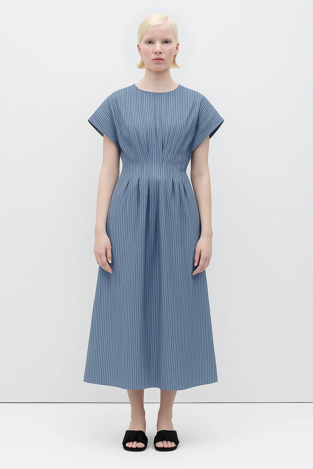 Woman wearing a Sybille Dress with blue stripes by Rita Row against a white background