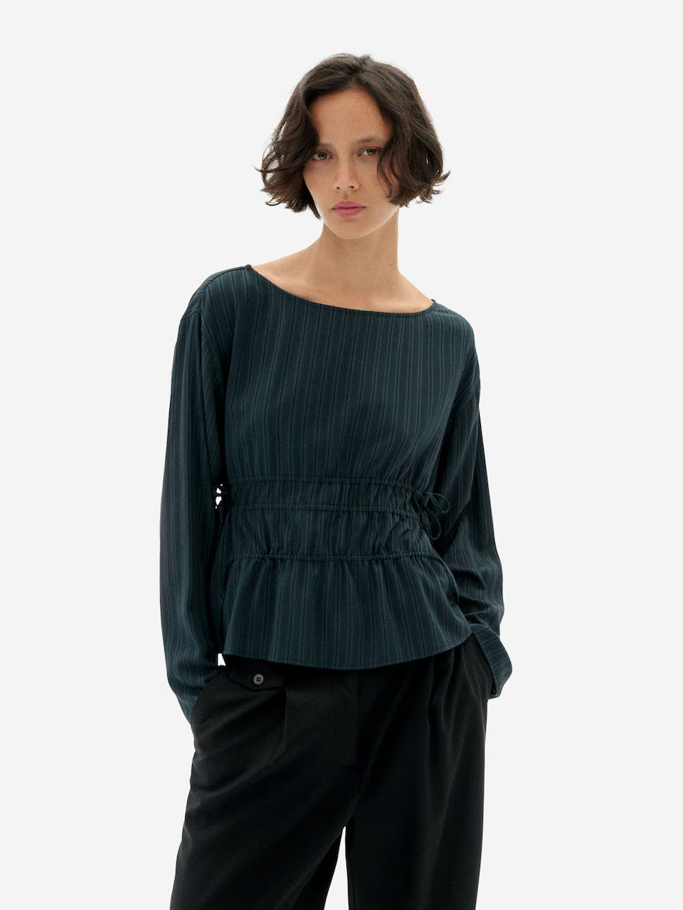 Woman waring Faded Dark Green striped Devin Blouse by Thinking Mu on a white background.