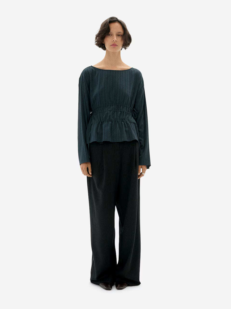 Woman waring Faded Dark Green striped Devin Blouse by Thinking Mu on a white background.