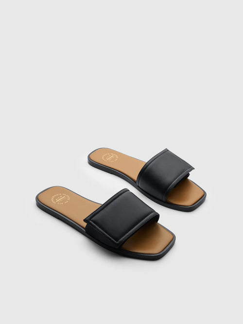 Black slide sandals with brown soles on a light gray background