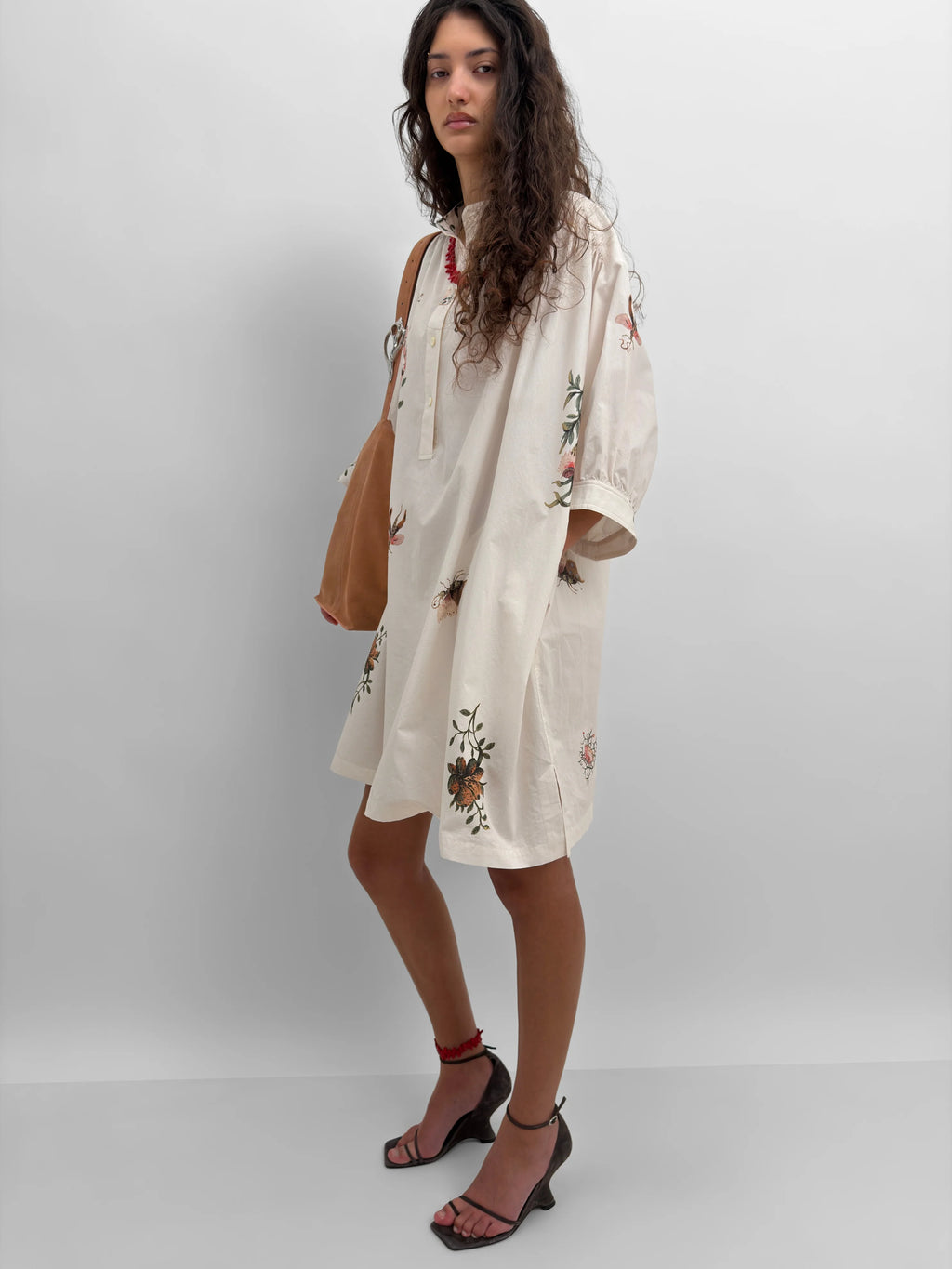 Woman wearing a white dress with floral print against a plain background