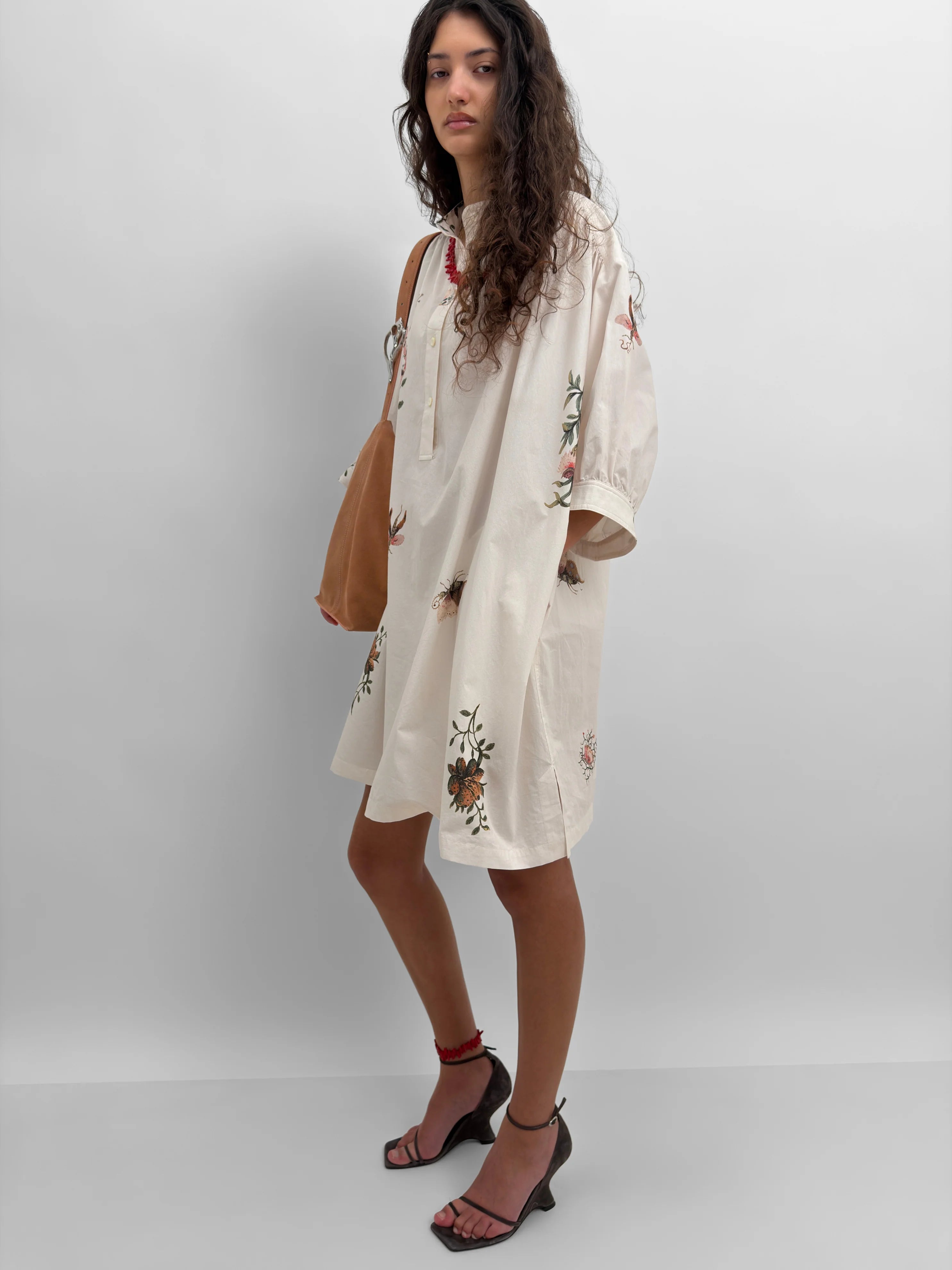 Woman wearing a white dress with floral print against a plain background