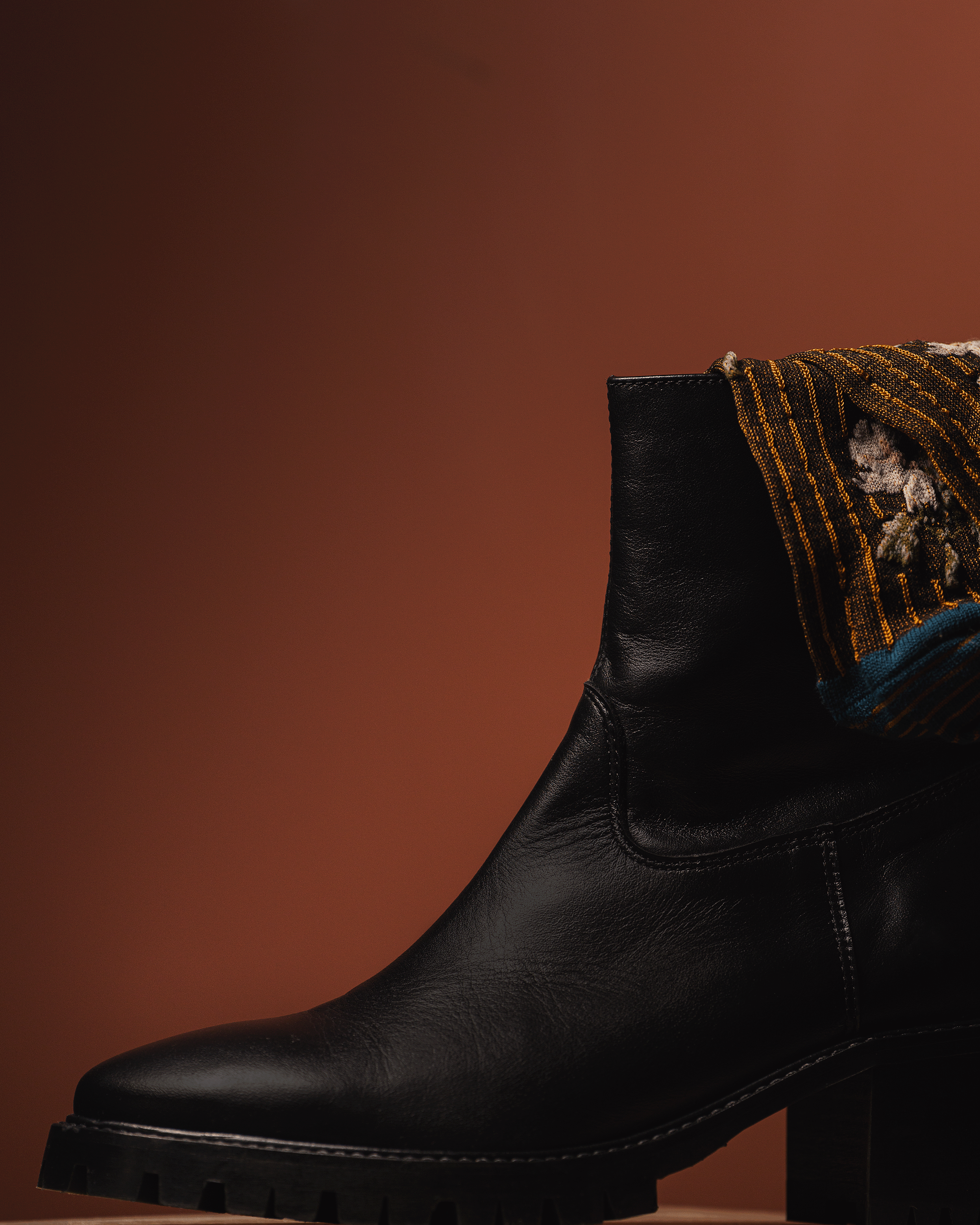 Black leather boot on a brown background