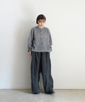 Person wearing a gray sweater and dark pants against a white background