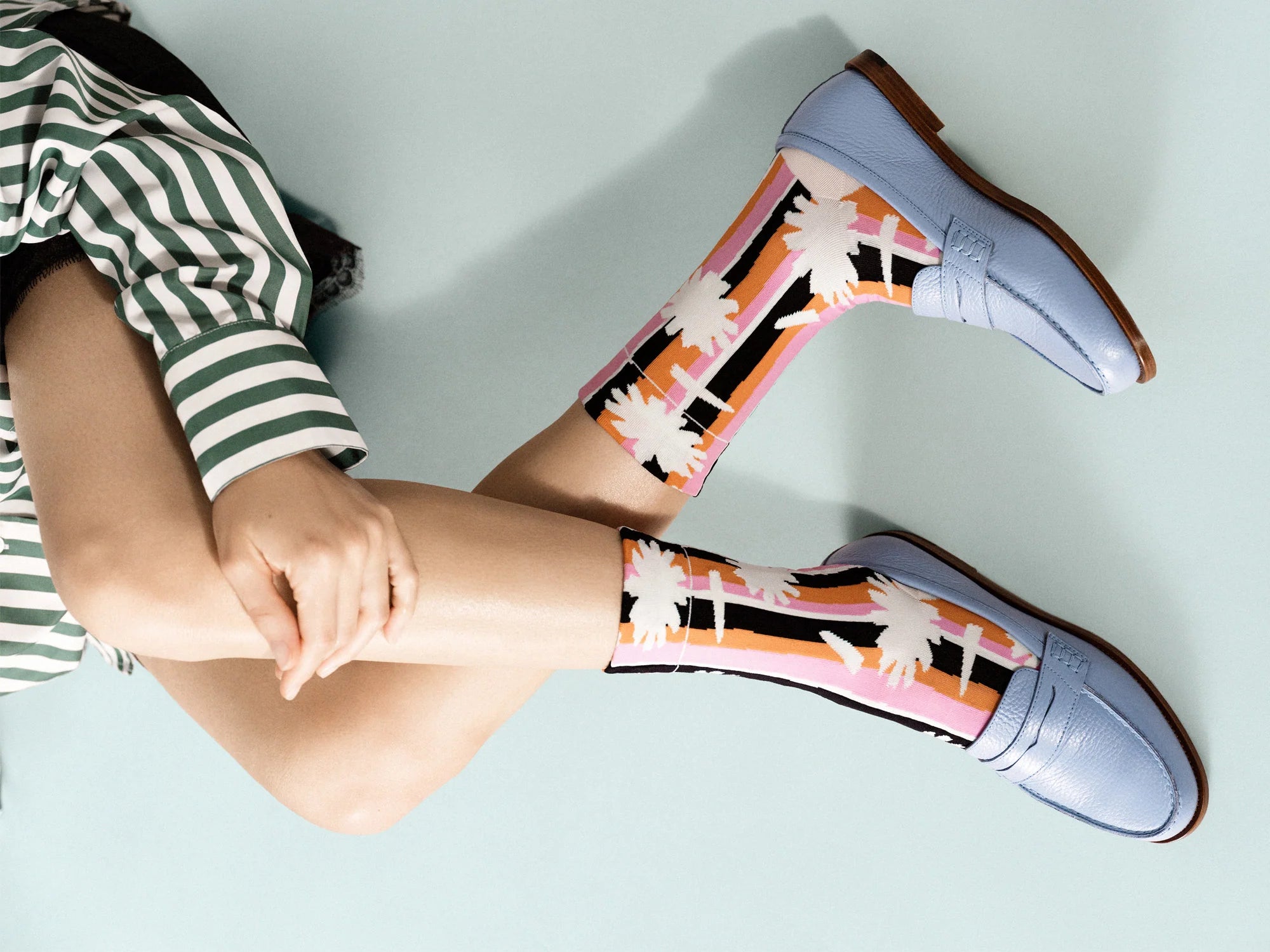 Person wearing colorful rain boots with a pattern on a light blue background