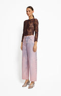 Model wearing a lace top and pink pants by Roseanna on a white background