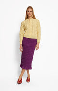 Woman wearing a yellow jacket and purple skirt on a white background