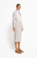 Woman wearing a white blouse and beige skirt on a white background