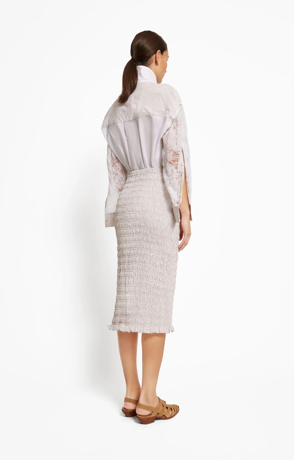 Woman wearing a white outfit with a beige textured skirt on a white background