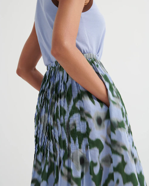 Woman wearing green/light blue Poet skirt by Kowtow with a light blue tank on a white background.