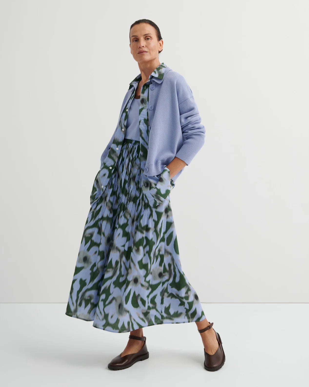 Woman wearing green/light blue Poet skirt by Kowtow with a light blue tank on a white background.