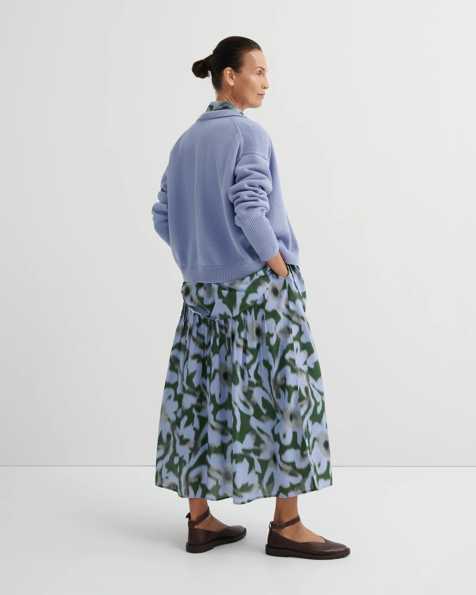 Woman wearing green/light blue Poet skirt by Kowtow with a light blue tank on a white background.