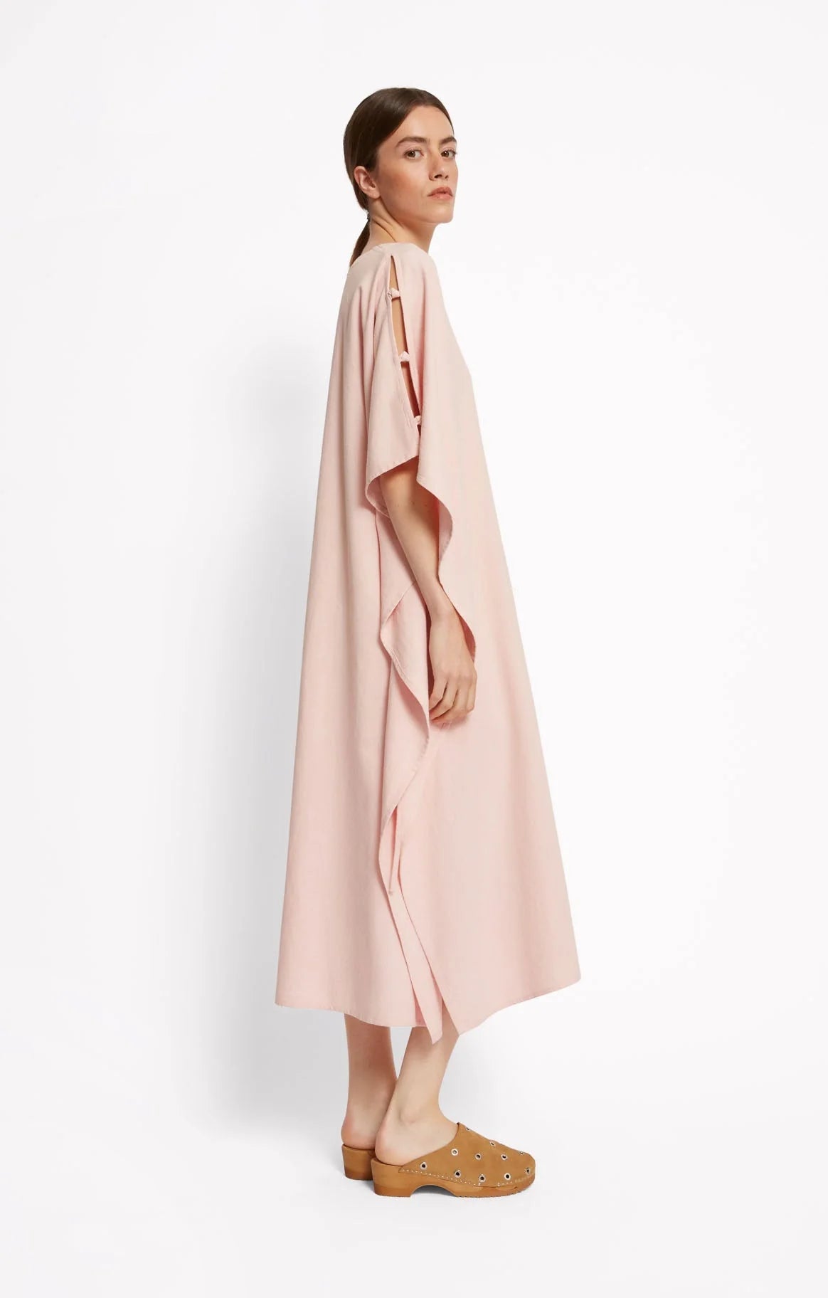 Woman wearing a light pink dress by Roseanna over a white background