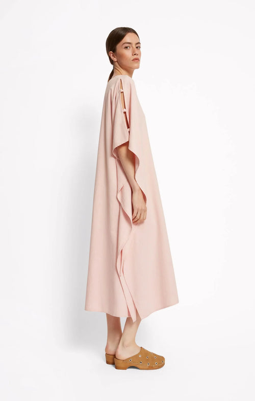 Woman wearing a light pink dress by Roseanna over a white background
