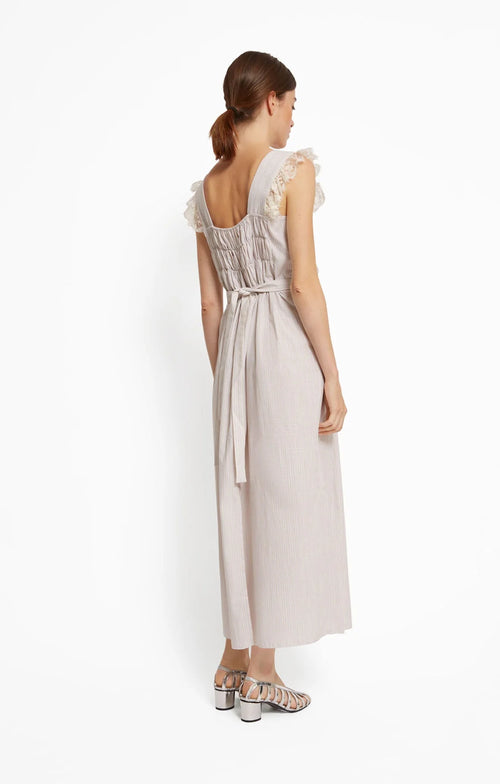 Woman wearing a beige with white stripes dress with lace details on a white background